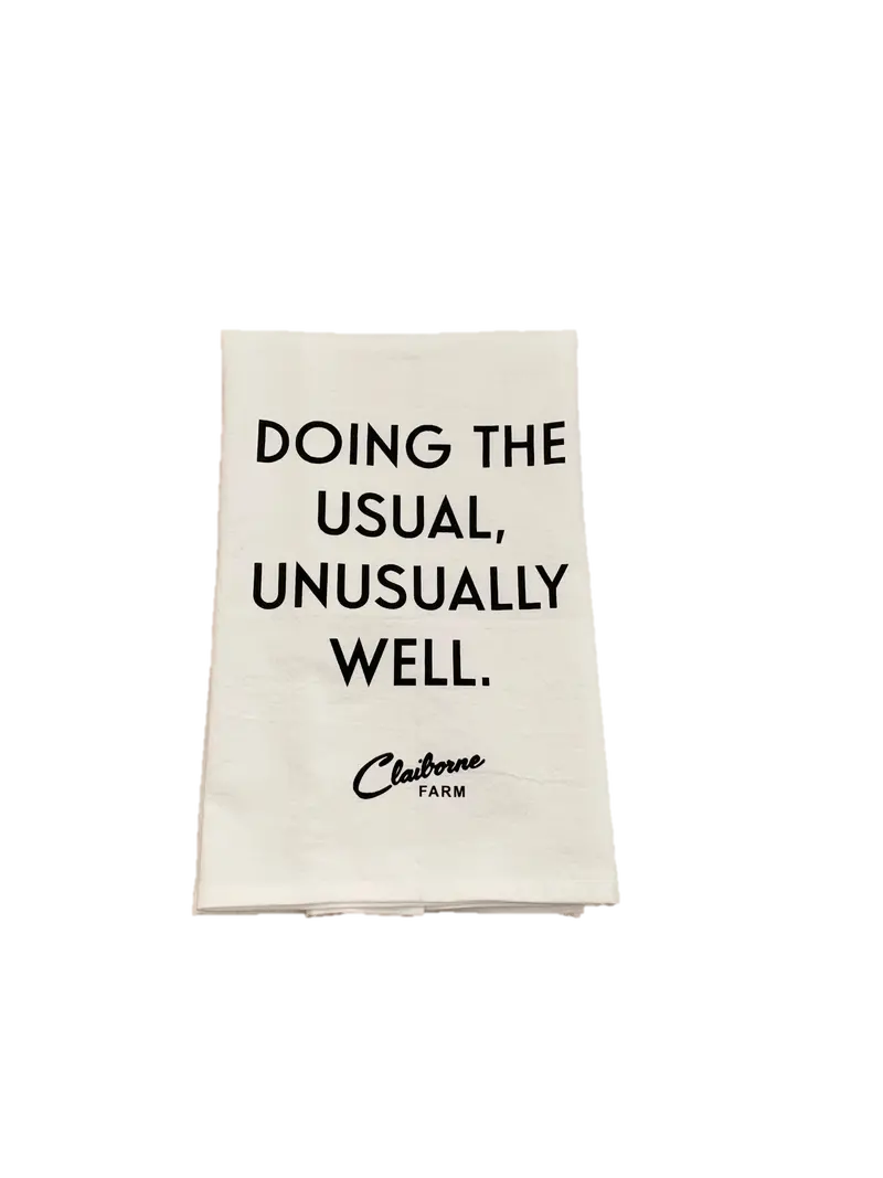 "Doing The Usual, Unusually Well" Motto Tea Towel 1